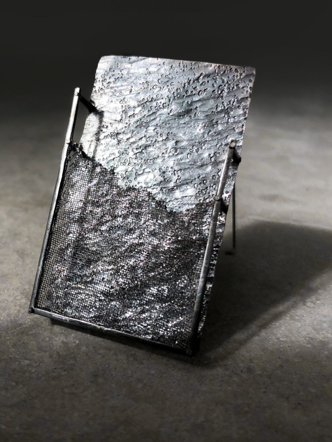 grey rectangle brooch on light grey concrete background
