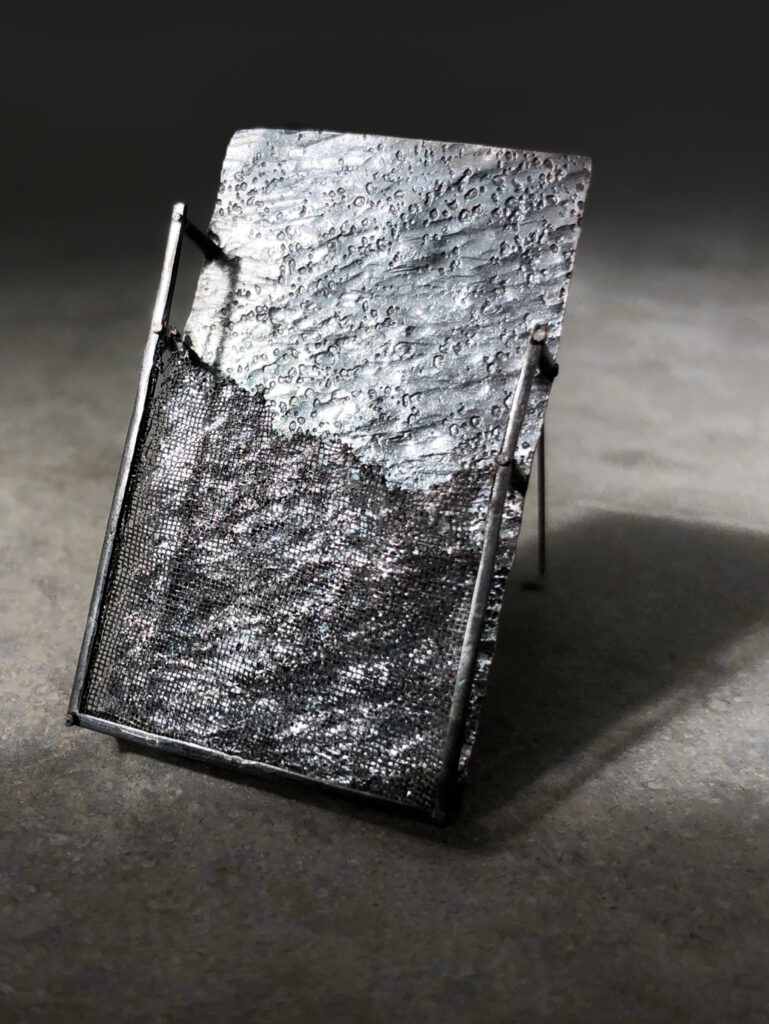 grey rectangle brooch on light grey concrete background